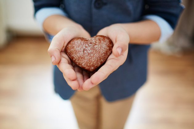 Boy carefully holding heart-shaped cookie